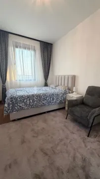 Furnished bedroom with a double bed, armchair, and window. - image 6