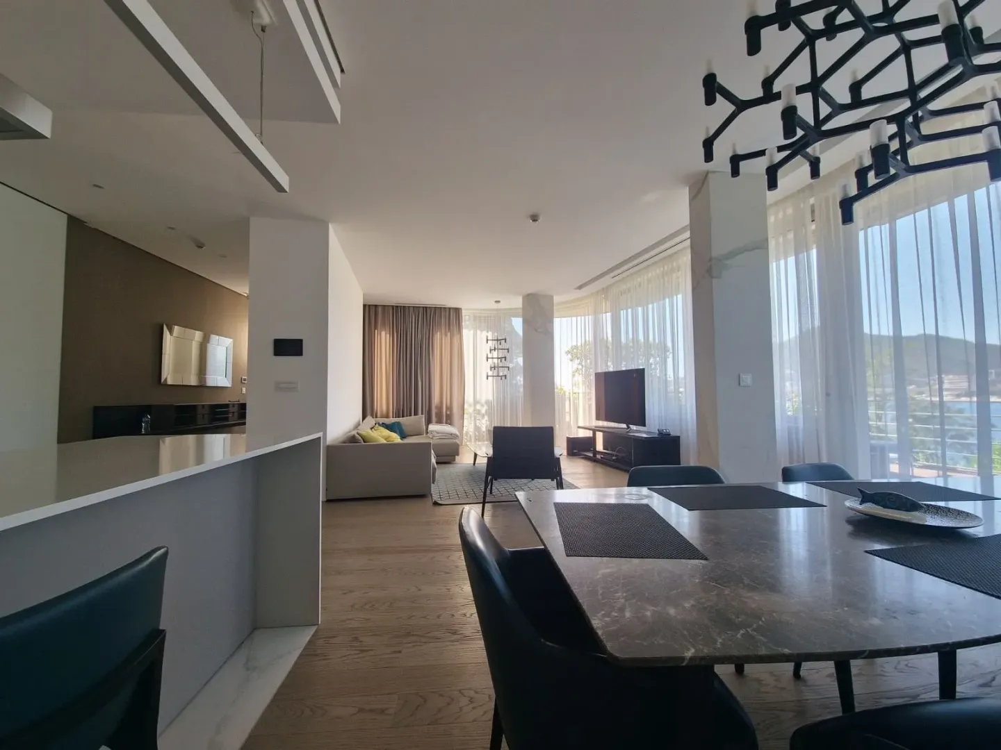 Spacious living room connected to the dining area and kitchen, featuring large windows with a sea view.
