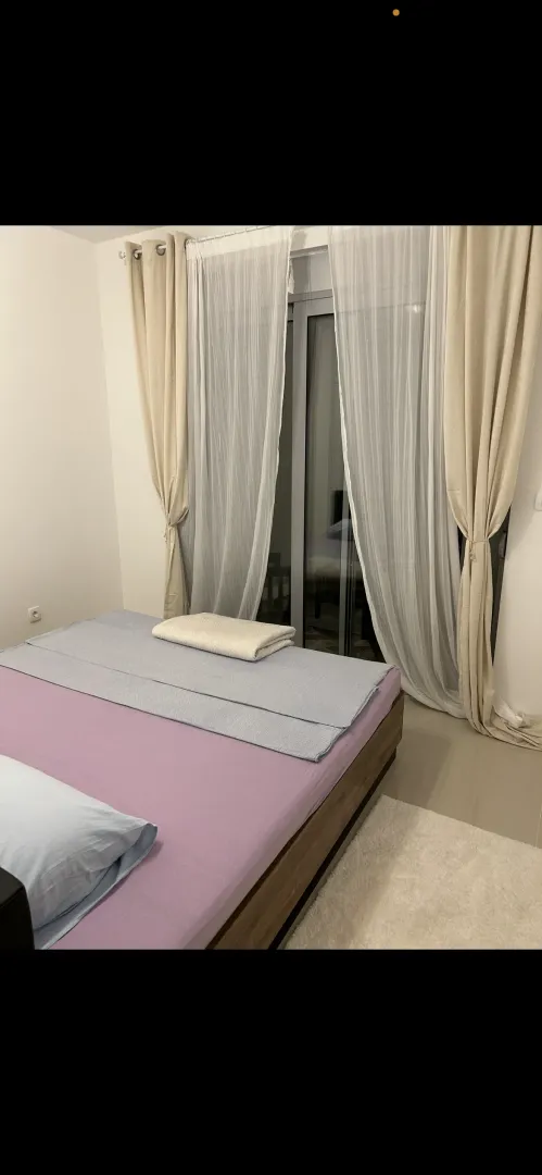 Spavaća soba sa bračnim krevetom i balkonskim vratima.