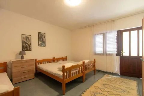 Spavaća soba sa drvenim krevetima, komodom i izlazom na terasu. - image 11
