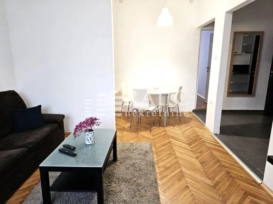 Dnevna soba sa garniturom i trpezarijskim delom u pozadini.