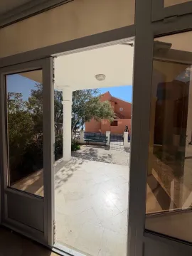 Pogled iz enterijera kroz otvorena vrata na popločano dvorište i okolne objekte. - image 8