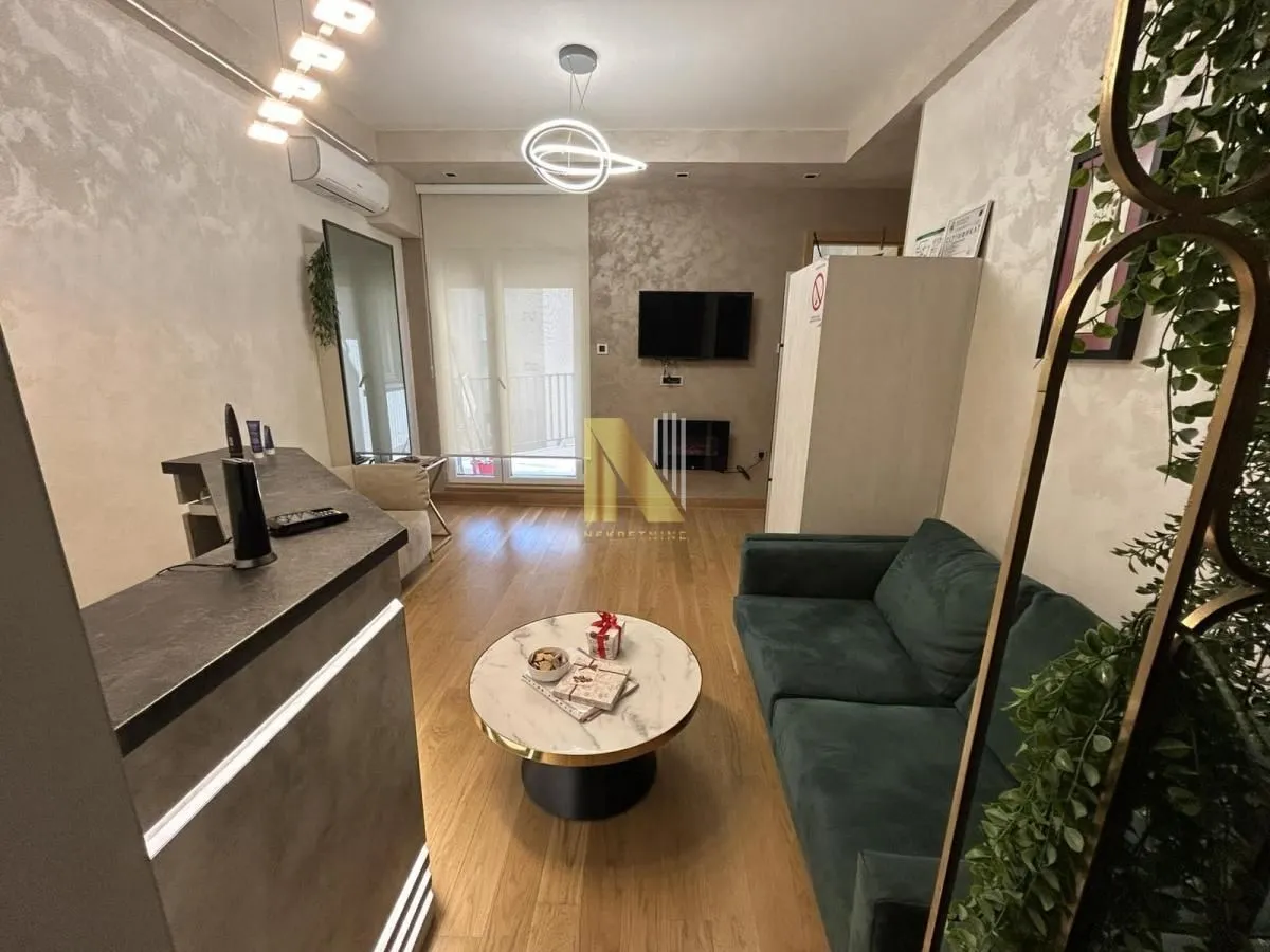 Living room with a green sofa, a round coffee table, and a wall-mounted TV.