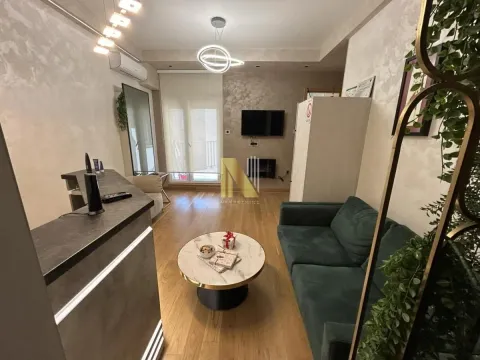 Living room with a green sofa, a round coffee table, and a wall-mounted TV. - image 6