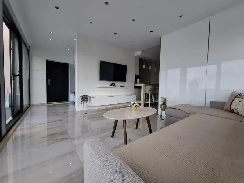Modern living room with a sofa, TV, and tiled flooring.
