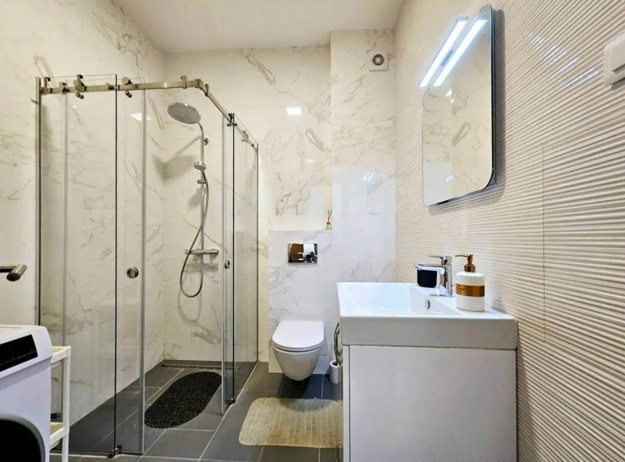 Moderne kupatilo sa tuš kabinom, umivaonikom i toaletom.