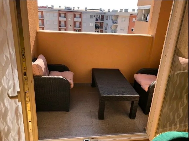 Namještena terasa sa garniturom za sedenje i pogledom na zgrade.