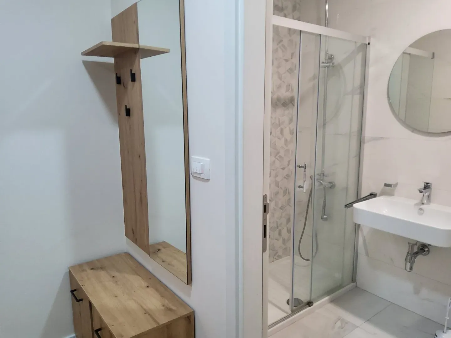 Bright bathroom with a shower cabin and part of the hallway with a mirror.