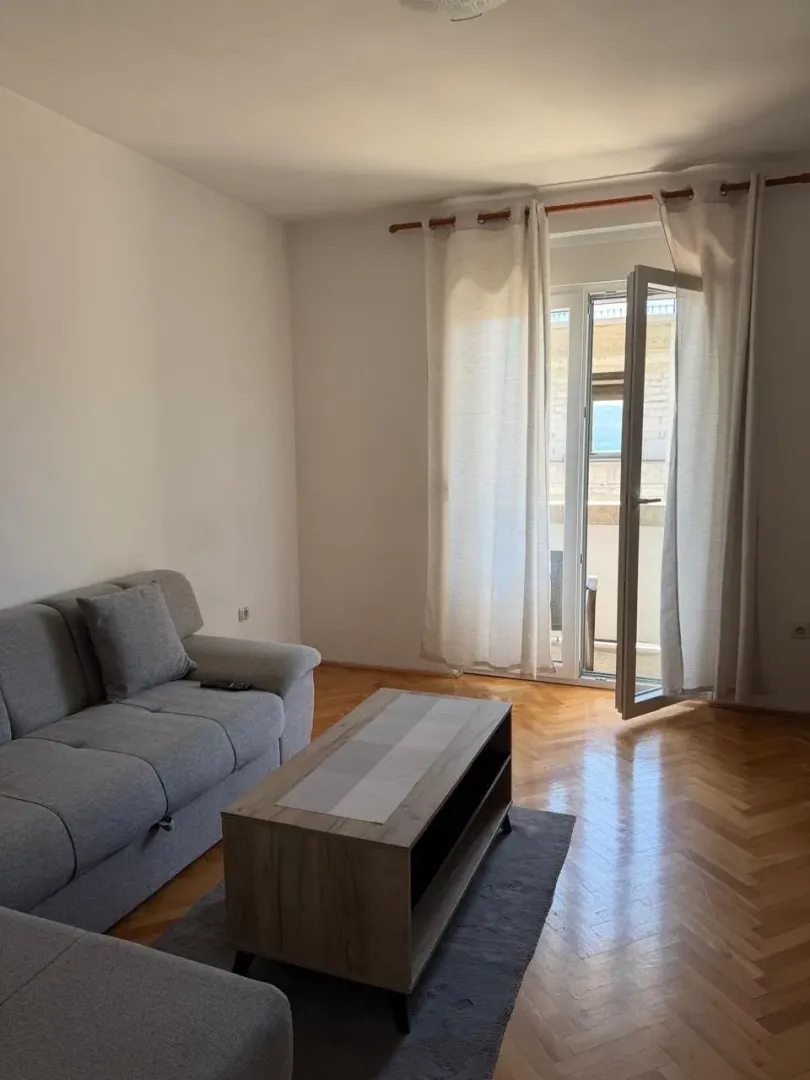 Dnevna soba sa garniturom, klub stočićem i izlazom na terasu.
