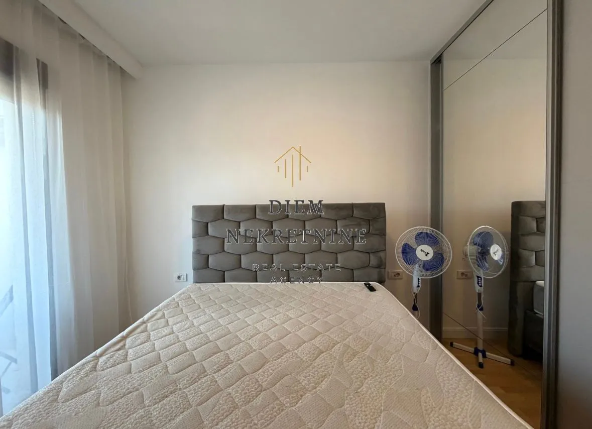 Spavaća soba sa bračnim krevetom, garderoberom i dva ventilatora.
