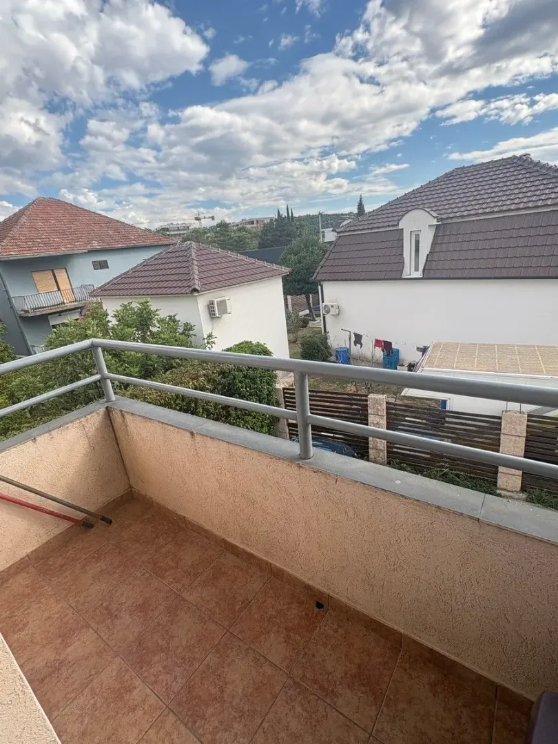 Pogled sa popločanog balkona na okolne kuće i dvorišta.