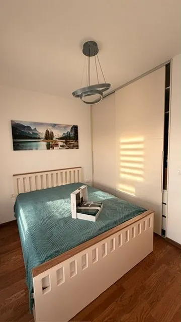 Furnished bedroom with a double bed, wardrobe, and a wall painting.
