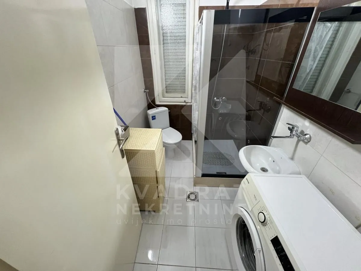 Bathroom equipped with a shower cabin, washbasin, toilet, and washing machine.