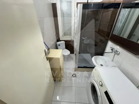 Bathroom equipped with a shower cabin, washbasin, toilet, and washing machine. - image 5
