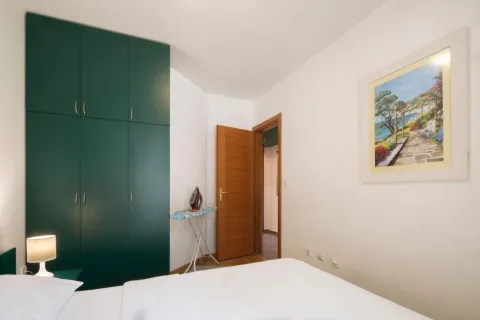 Spavaća soba sa velikim zelenim garderoberom, krevetom i slikom na zidu. - image 6