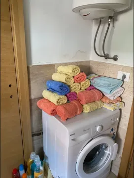 Bathroom with a washing machine and folded towels. - image 6