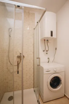 Bathroom with a shower cabin, water heater, and washing machine. - image 15