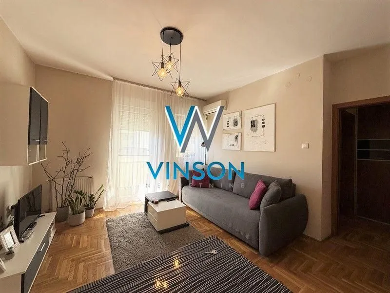 Dnevna soba sa garniturom, televizorom i trpezarijskim stolom.