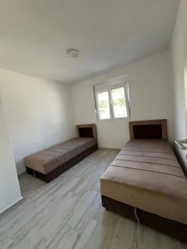 Spavaća soba sa dva singl kreveta i bijelim zidovima. - image 3