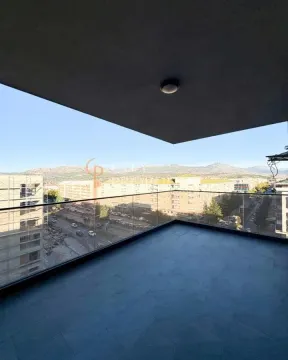 Spacious covered balcony with a glass railing and city views. - image 3