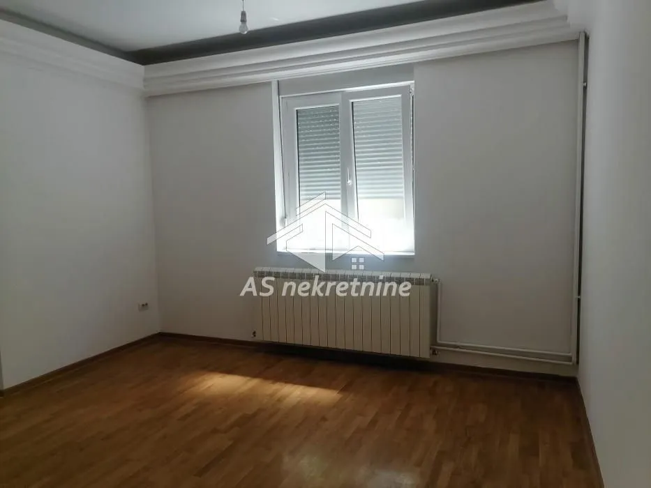 Prazna soba sa parketom i prozorom.