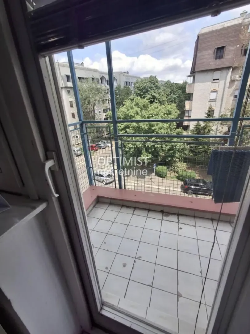 Pogled sa balkona na okolne zgrade i zelenilo.