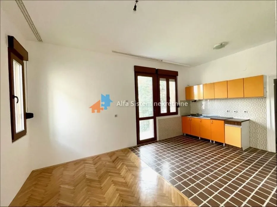 Empty kitchen with orange cabinets and parquet flooring.