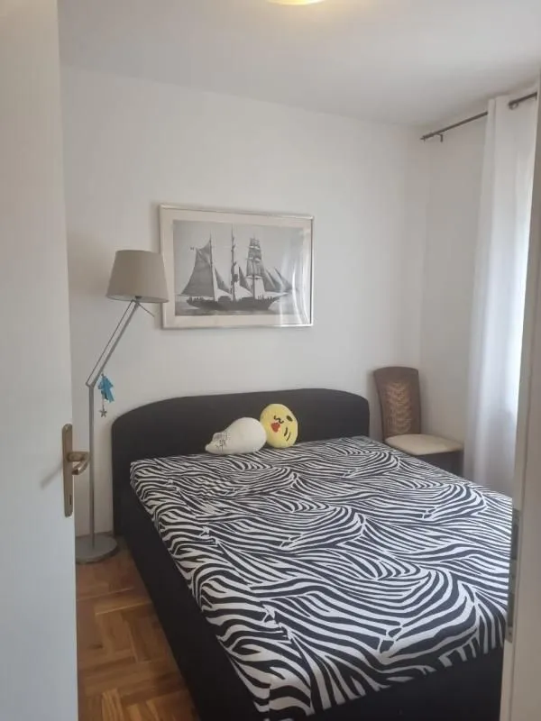 Spavaća soba sa bračnim krevetom, podnom lampom i umjetničkom slikom na zidu.