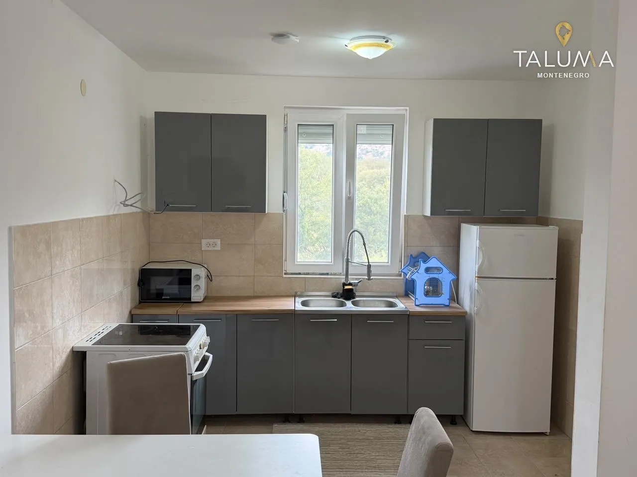 Kitchen with grey cabinets, a sink, stove, and refrigerator.