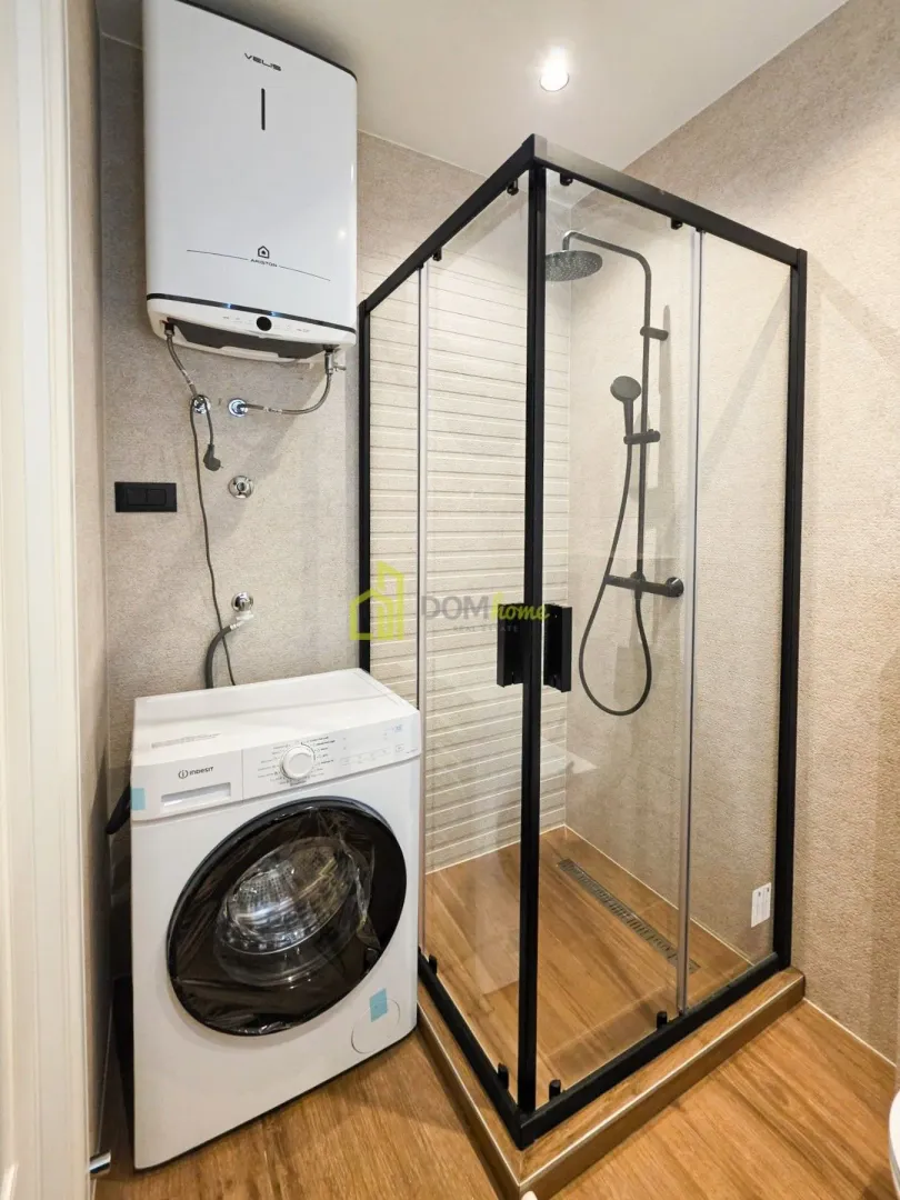 Bathroom with a shower cabin, water heater, and washing machine.