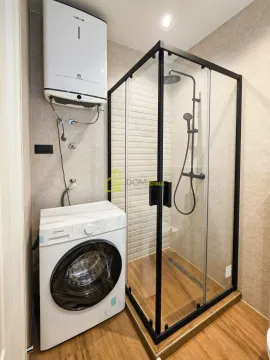 Bathroom with a shower cabin, water heater, and washing machine. - image 4