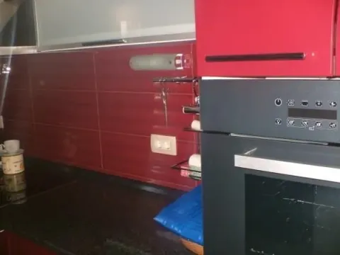 Kitchen with built-in oven and red details. - image 8