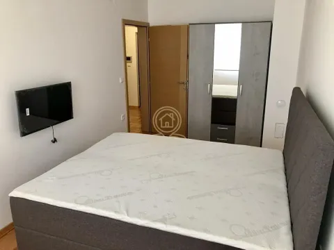 Nameštena spavaća soba sa bračnim krevetom, garderoberom i televizorom na zidu. - image 7