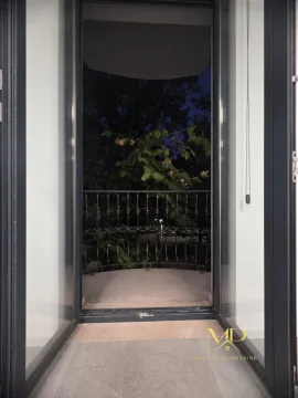 View through balcony doors onto the terrace and greenery at dusk. - image 8