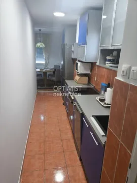 Narrow kitchen with cabinets and a dining area in the background. - image 3