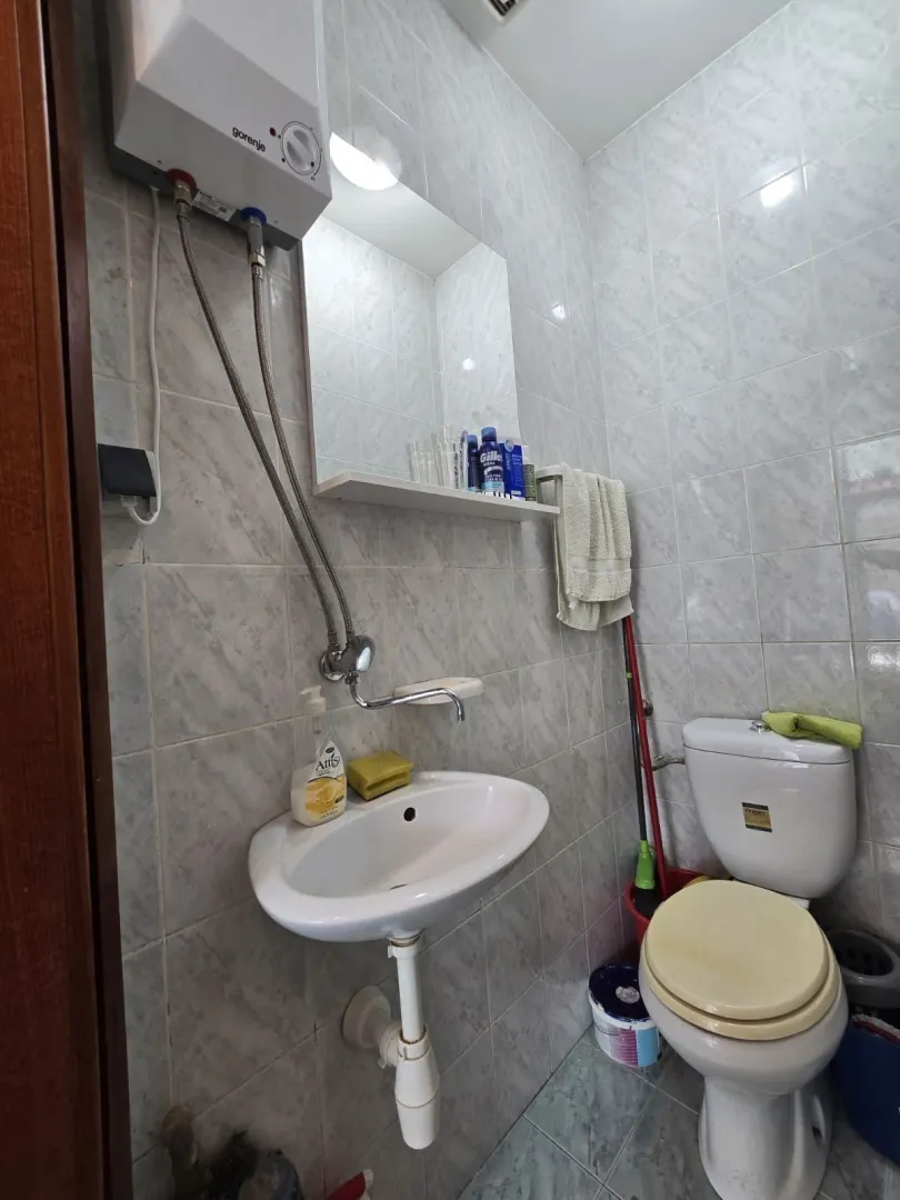 A small bathroom with a sink, mirror, and toilet.