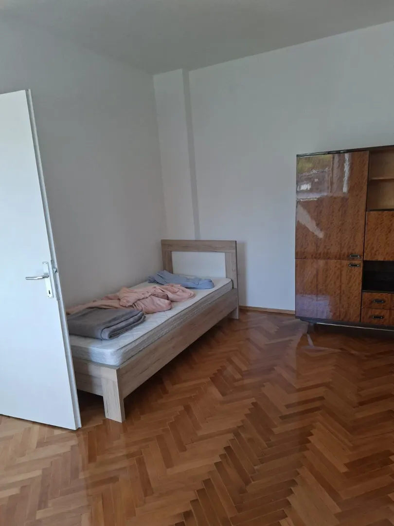 Spavaća soba sa singl krevetom i drvenim regalom.