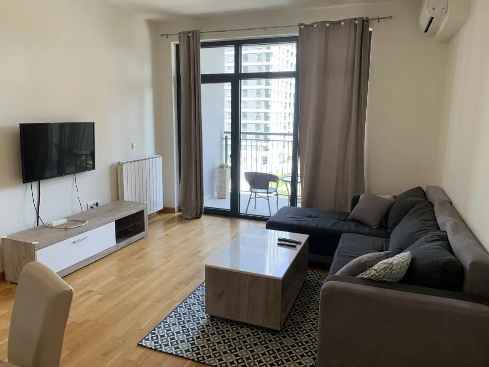 Living room with a sofa, TV, and balcony access.