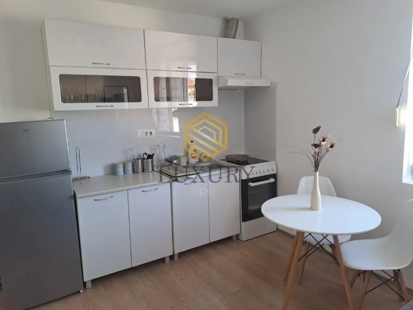 Small white kitchen with a dining table and refrigerator.