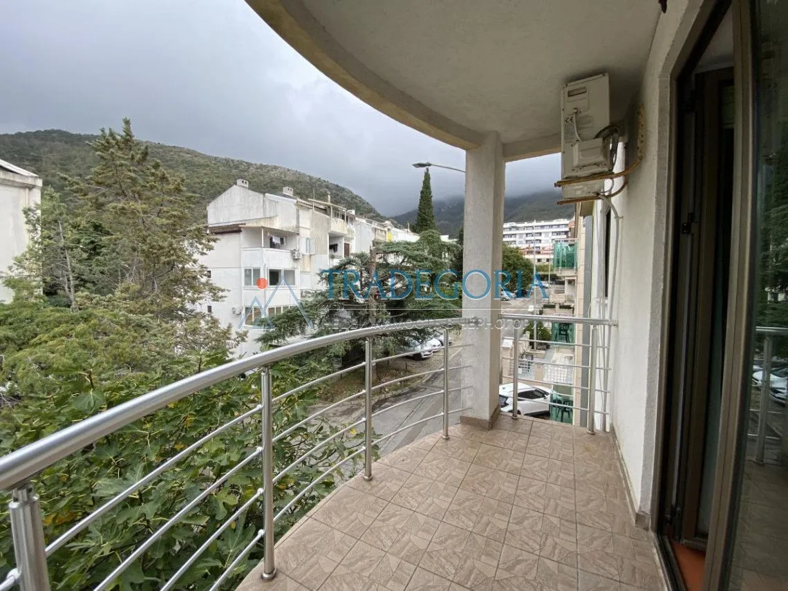 Covered balcony with a view of the street and greenery.
