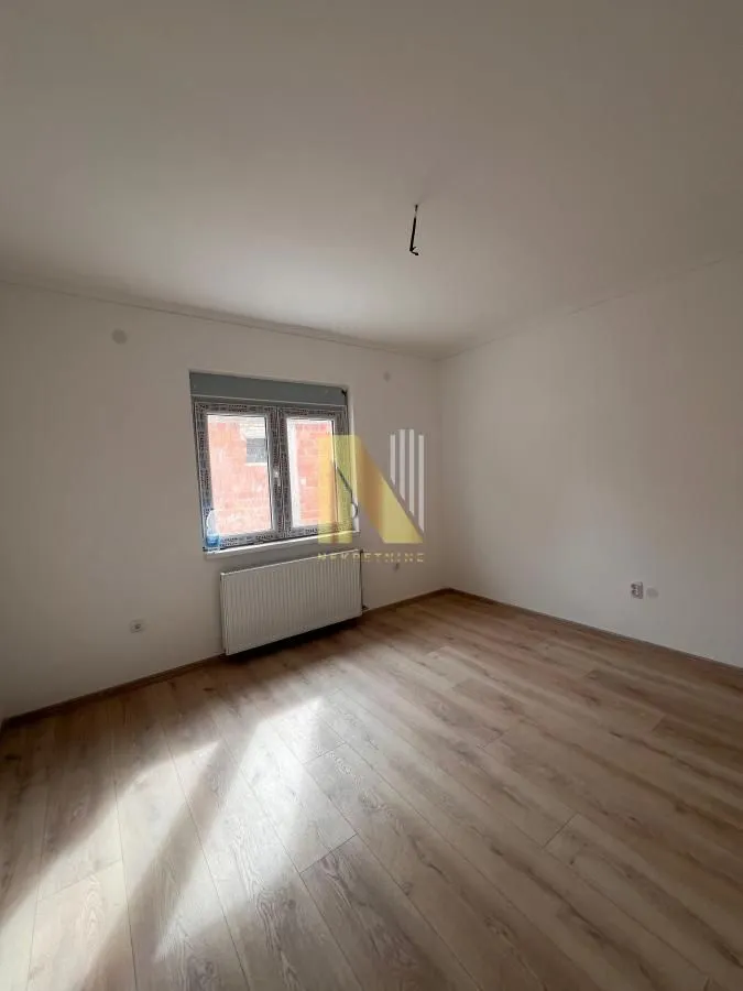 Prazna soba sa laminatom i belim zidovima.