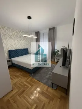 Nameštena spavaća soba sa bračnim krevetom, TV komodom i parketom na podu. - image 9