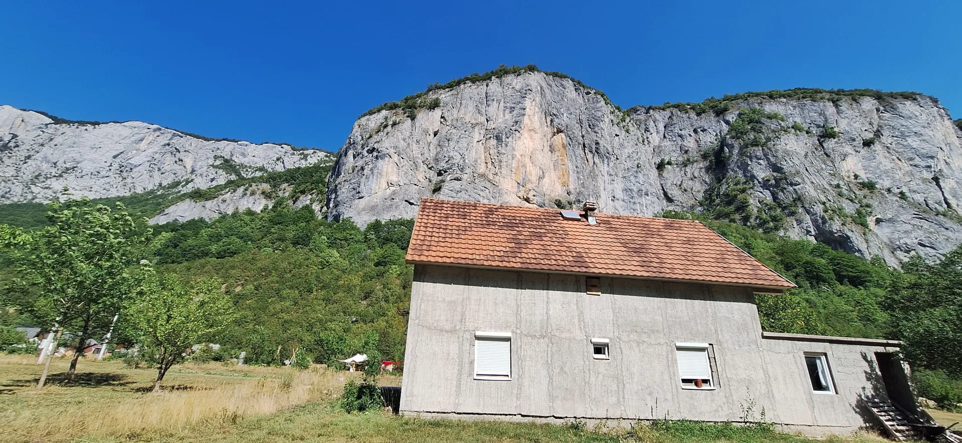 Pogled na kuću u prizemlju sa velikom stijenom u pozadini.