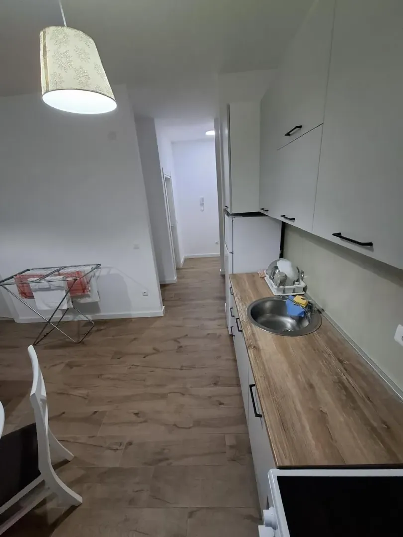 Small kitchen with a wooden countertop and white cabinetry in an apartment.