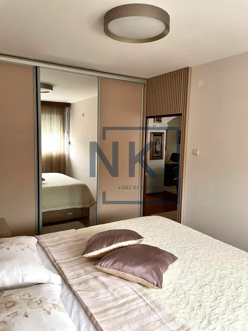 Furnished bedroom with a large mirrored wardrobe.