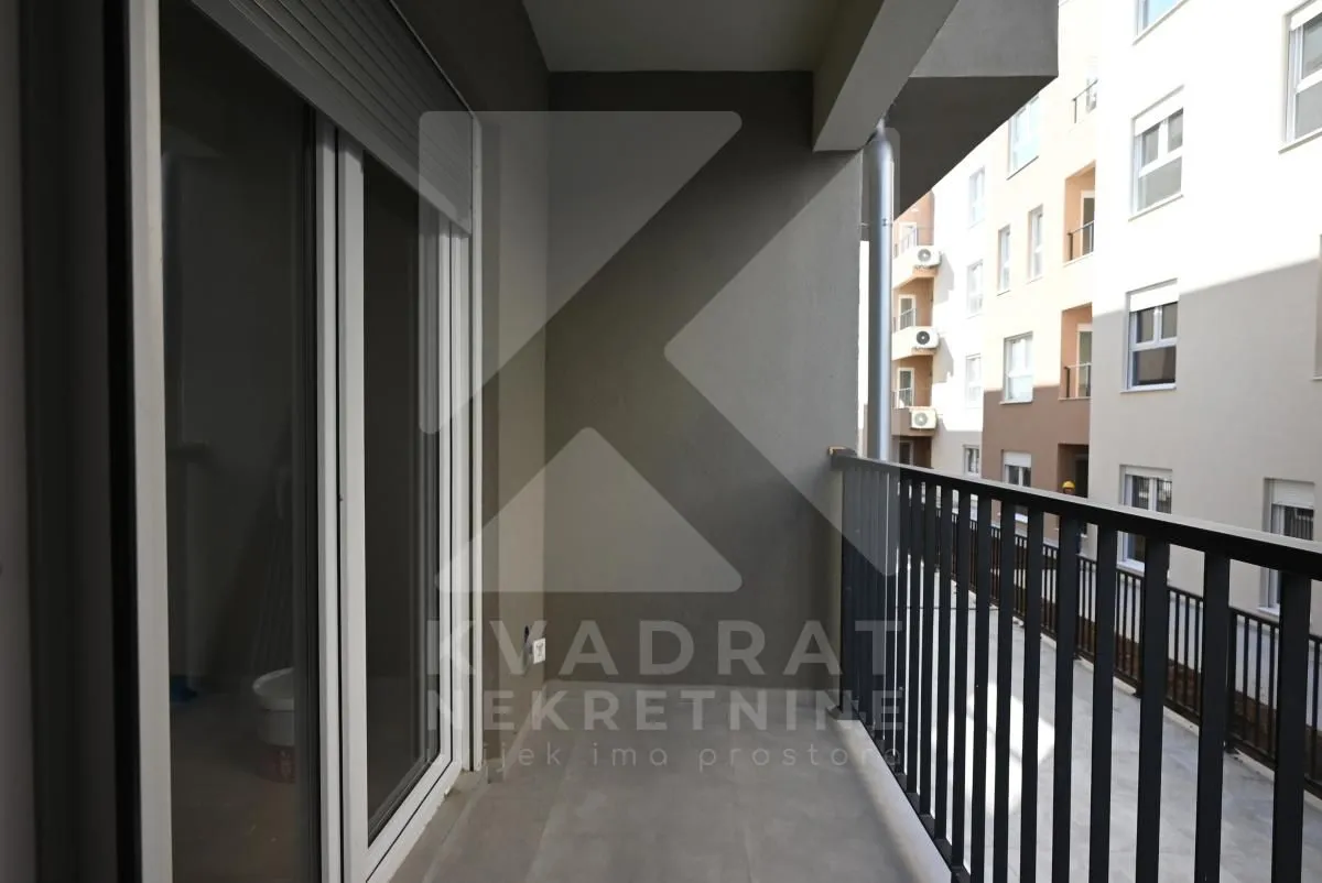 Nenamješten balkon sa pogledom na susjednu zgradu.