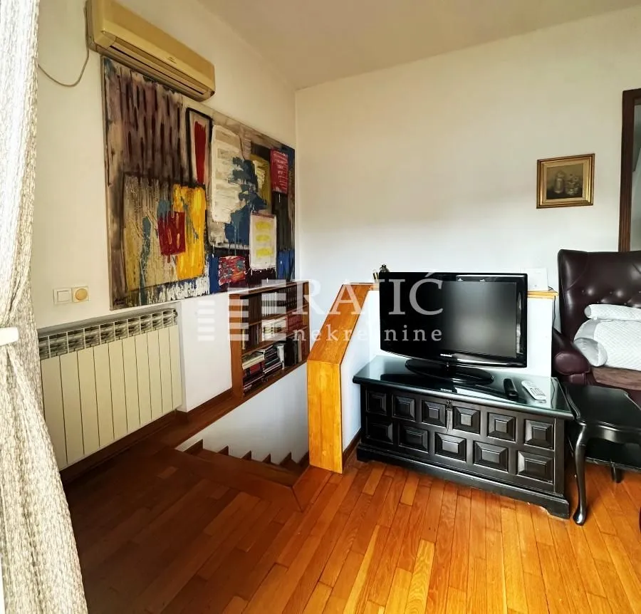 Living room with wooden flooring, TV, and a staircase.