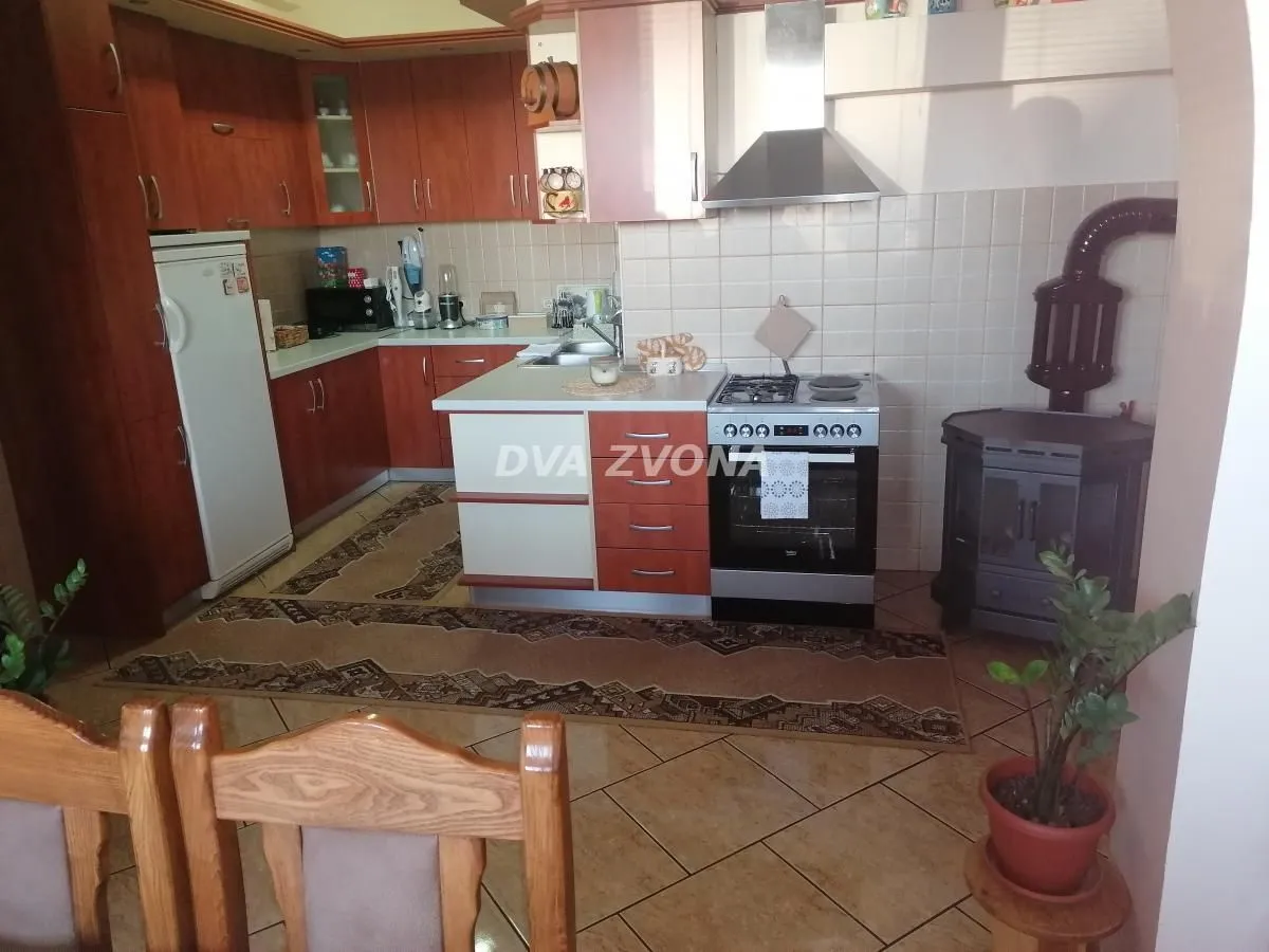 Kitchen with wooden cabinetry, a stove, and a solid fuel stove in the corner.