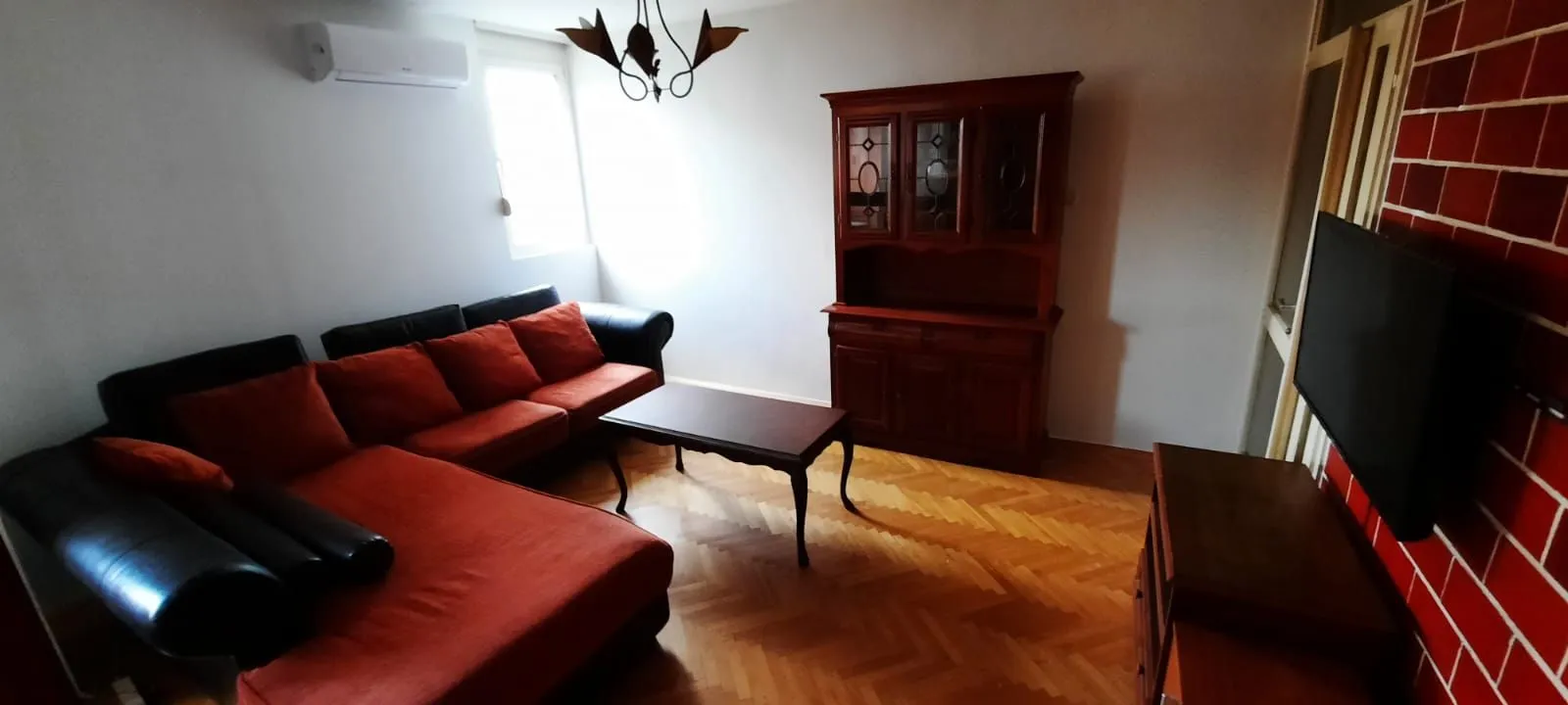 Living room with sofa set, wooden furniture and television.