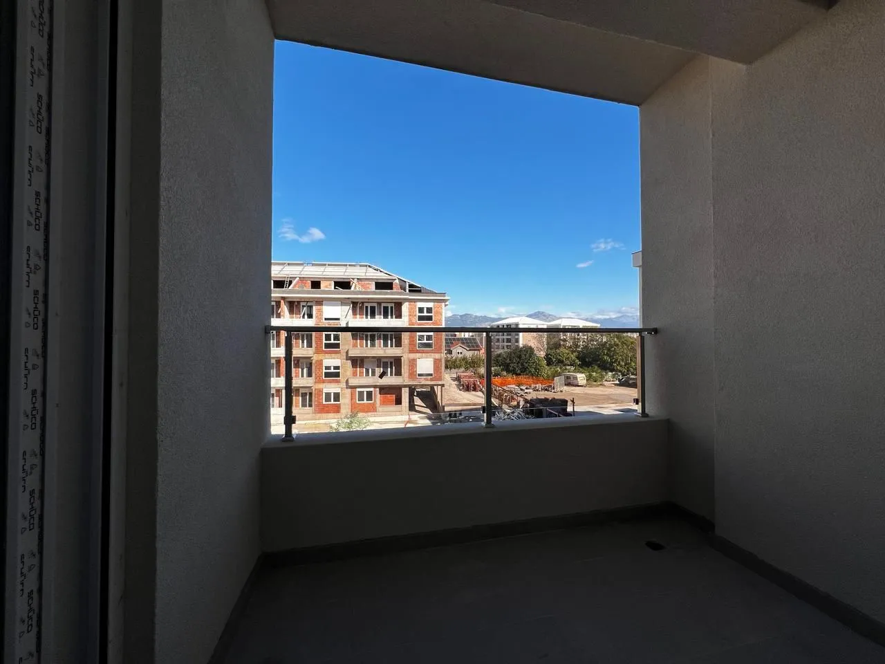 Natkriveni balkon sa pogledom na okolne zgrade i planine.